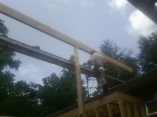 Carpenter setting a ridge beam over a new addition frame — Ice Dam Removal by Roofing Brothers in Kerrville