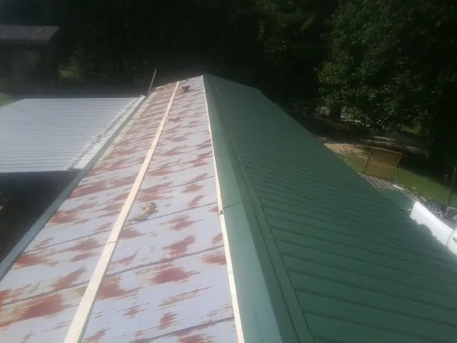 Old rusted panels beside newly installed green metal roofing — Wind Damage Roof Repair by Roofing Brothers in Kerrville