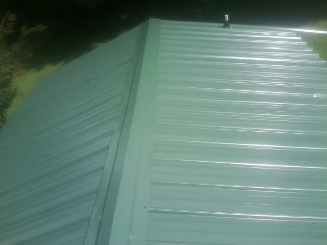 New green metal panels meeting at the ridge of a roof — Flat Roof Repair work by our crew in Kerrville