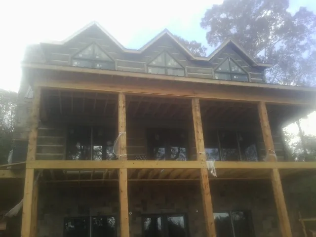 Dormers and porch framing on a large log home under construction — Roof Coating work by our crew in Kerrville