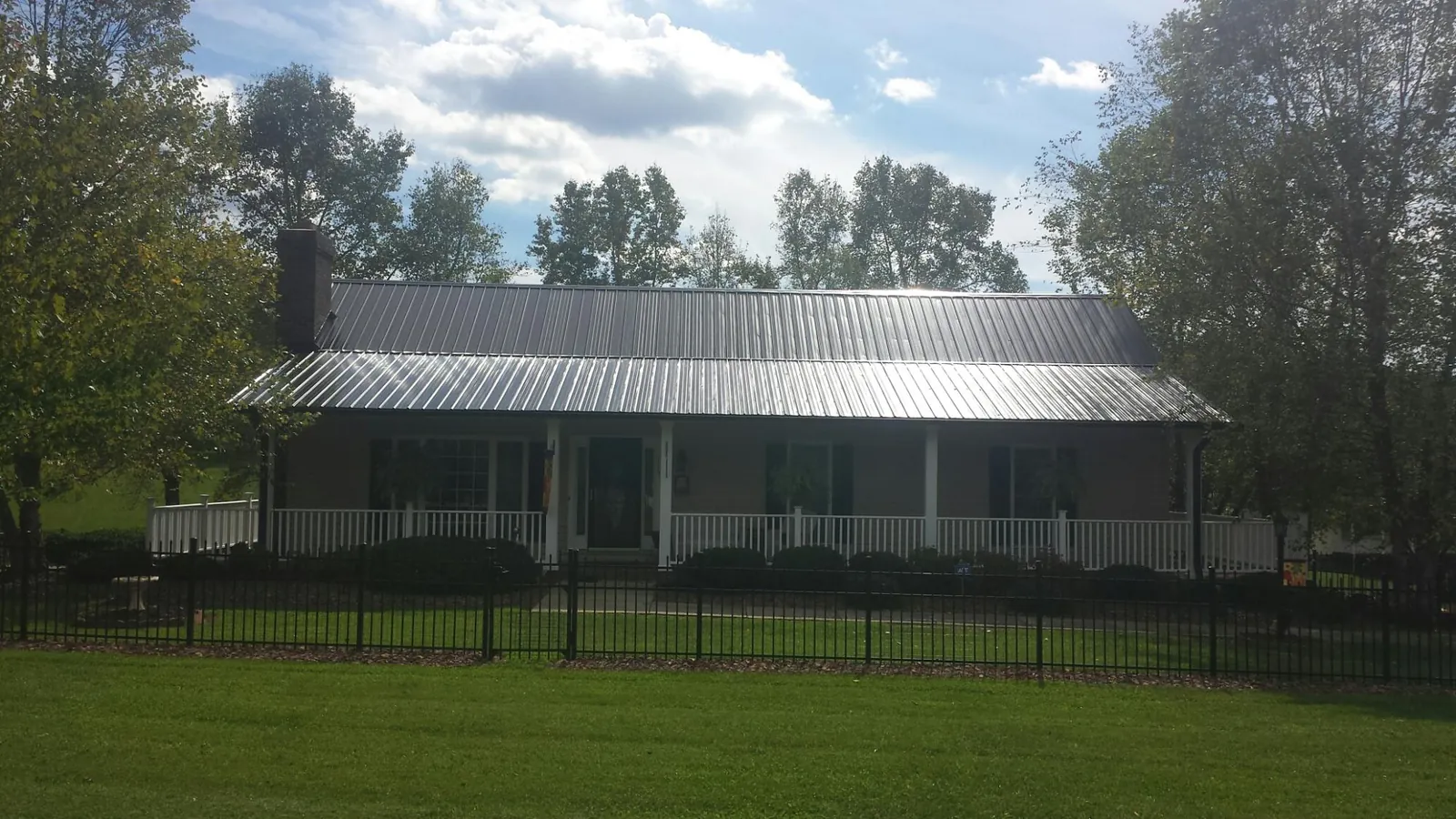 Gray metal roof on a brick ranch with a full width front porch — Gutter Guard Installation work by our crew in Kerrville