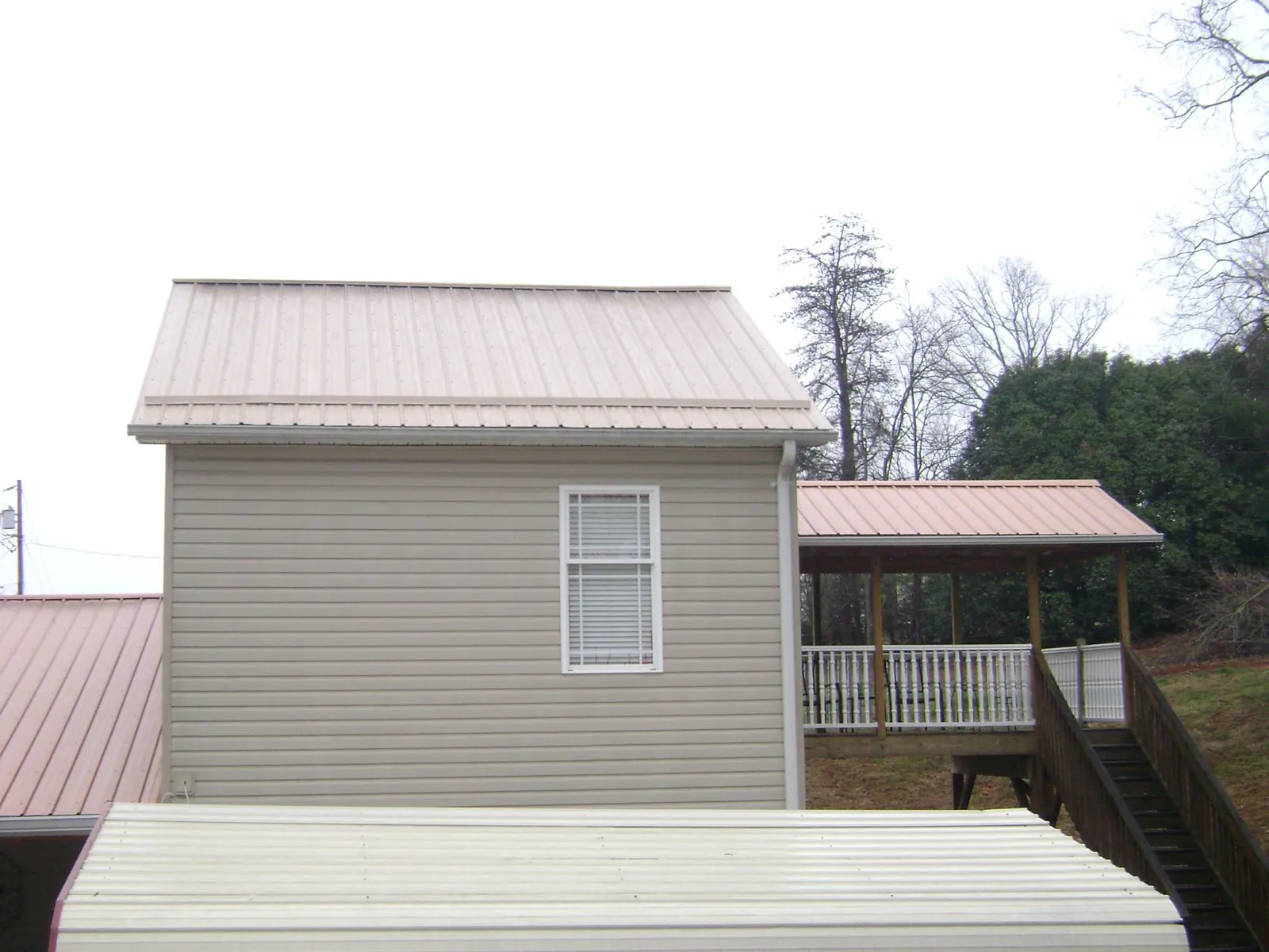 Tan metal roofs on a two story addition and attached porch, from a Roof Replacement job in Kerrville