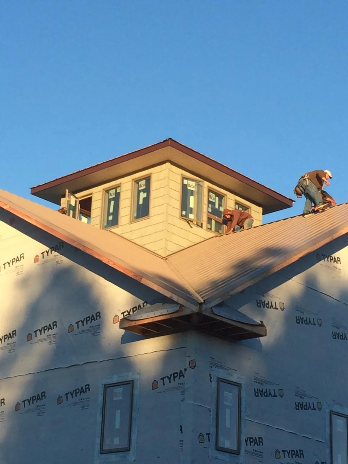 Roofers working around a rooftop cupola on a new metal roof at sunset — Roof Waterproofing in Kerrville by Roofing Brothers